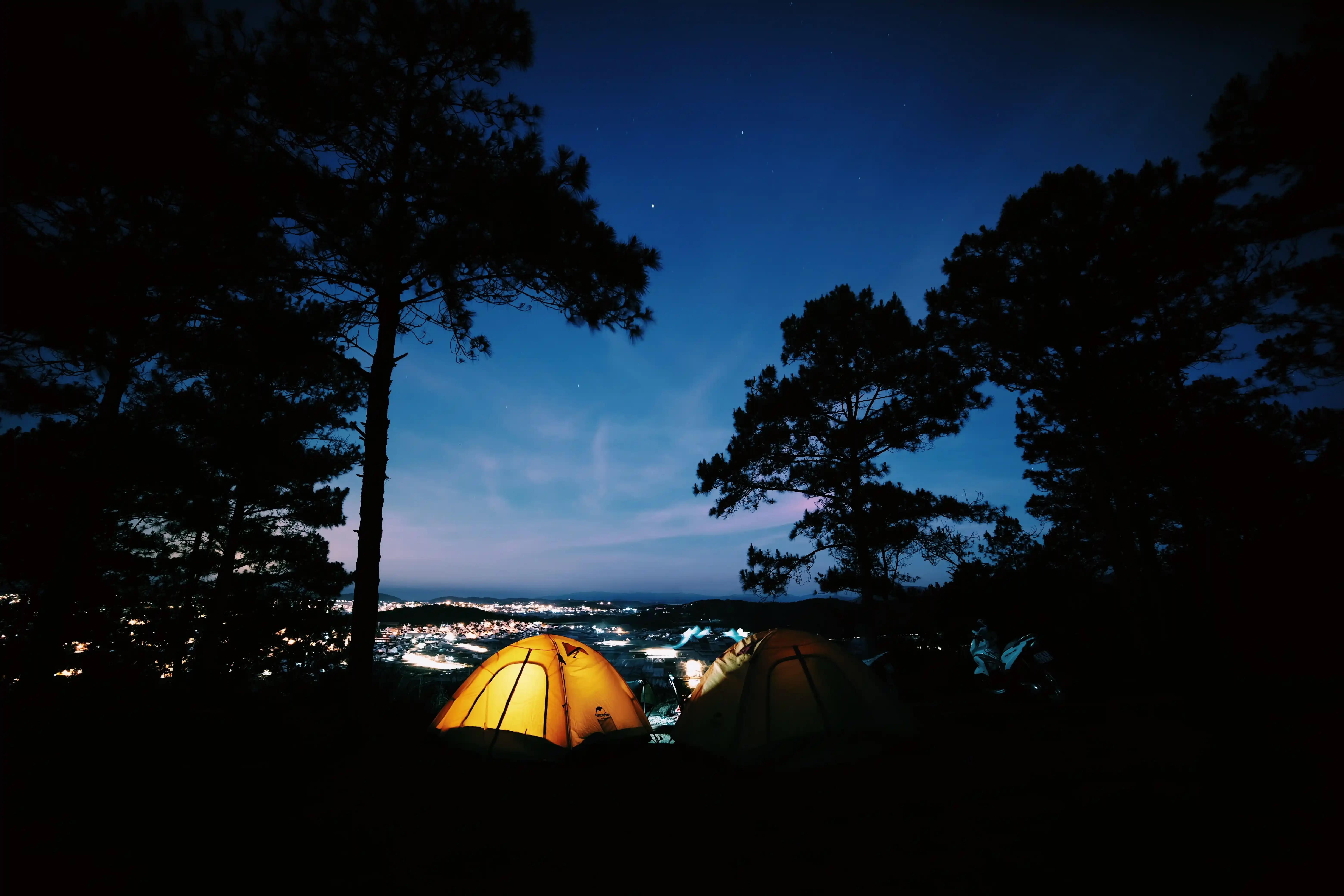 Two glowing camping tents under a star-filled night sky in a dark-sky reserve